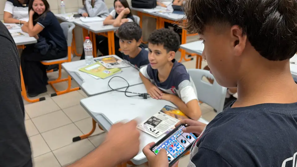 A TIS student driving a robot from a phone controller while classmates watch